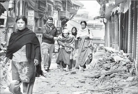  ?? Hemanta Shrestha
European Pressphoto Agency ?? IN KATMANDU, people head off to look for a place to shelter. Thousands camped in the rain in Nepal’s capital, afraid aftershock­s could bring down more buildings.