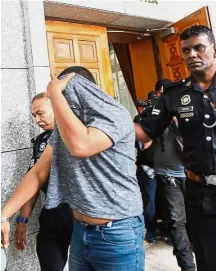  ??  ?? Record offender: The accused hiding his face from photograph­ers as he is escorted out of the court room.