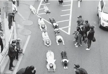  ?? LEE JIN-MAN/AP ?? Anti-coup protests expand: Buddhist monks and Myanmar nationals lie on a road Friday during a protest near Myanmar’s embassy in Seoul, South Korea. The action is in response to last month’s military coup in Myanmar. Also on Friday, police in Myanmar continued cracking down by firing rubber bullets and tear gas at protesters in two major cities.