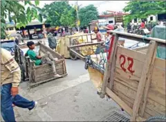  ?? KHOUTH SOPHAK CHAKRYA ?? Porters pull a cart loaded with goods across the Thai-Cambodia border as others wait for jobs in Poipet in 2015.