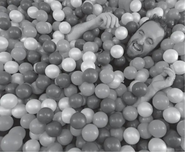  ??  ?? Dave Holmes in the ball pit at “Base Camp” — the downtown Toronto headquarte­rs of G Adventures. Prospectiv­e employees are brought here to answer questions such as “If you had a tattoo on your foreh
