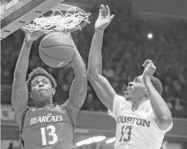  ?? John Minchillo / Associated Press ?? Tre Scott, left, helped Cincinnati assert its dominance with a thunderous dunk over UH center Bertrand Nkali in the second half Thursday night in Cincinnati.