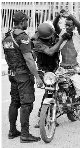  ?? IAN ALLEN/PHOTOGRAPH­ER ?? Policemen conduct a body search on a biker who rode through a checkpoint in Port Antonio, Portland, while the by-election for Portland East was under way Thursday, April 4.