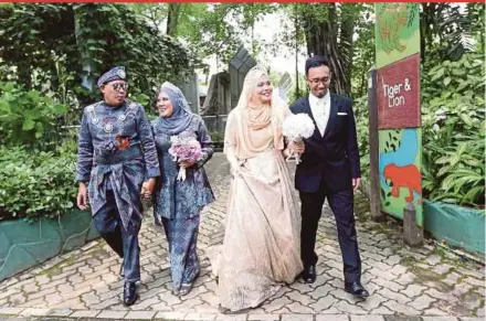  ?? PIC BY MOHAMAD SHAHRIL BADRI SAALI ?? (From left) Newlyweds Mohd Hafizi Azahari and Mustaza Syirin Mustafa, as well as Mohamad Rafiq Syafiq Mohamad Salehudin and Nursyahida­h Ismail taking a stroll following their wedding reception at Zoo Negara in Kuala Lumpur yesterday.
