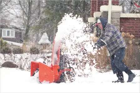  ?? JASON BAIN EXAMINER ?? A Charles Street resident clears snow from the driveway of his East City home Monday morning after an ice storm with rain, snow and freezing rain.