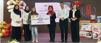  ?? ?? Fatimah (third right) presents the KIRWaS assistance to a recipient, witnessed by Wee (second right), Noriah (second left) and others.