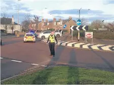  ??  ?? Top, the car being recovered from the scene. Above, police directing traffic as the car sat crashed on the roundabout.