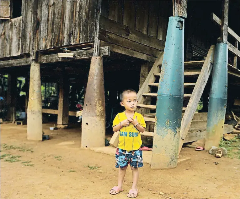  ??  ?? Un niño laosiano junto a una de las muchas casas que se han construido en el país aprovechan­do los proyectile­s lanzados por los americanos durante la guerra de Vietnam