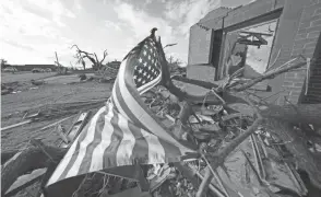  ?? GERALD HERBERT/AP ?? A flag flies Tuesday amid debris of destroyed homes in Mayfield, Ky., in the aftermath of tornadoes that tore through the region.
