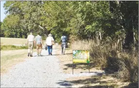  ?? Westside Eagle Observer/SUSAN HOLLAND ?? Wes Stabel (left) and other members of the Decatur Seventh-day Adventist Church walk down the trail behind the church past one of 30 signs inscribed with Bible verses that are placed along the length of the trail. Stabel suggested the church establish the trail and put up signs after visiting a similar trail at Weimar College in Weimar, Calif.