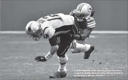  ?? Photo: AFP ?? Tom Brady(left) of the New England Patriots is sacked by Bobby McCain of the Miami Dolphins on Sunday in Miami, Florida.