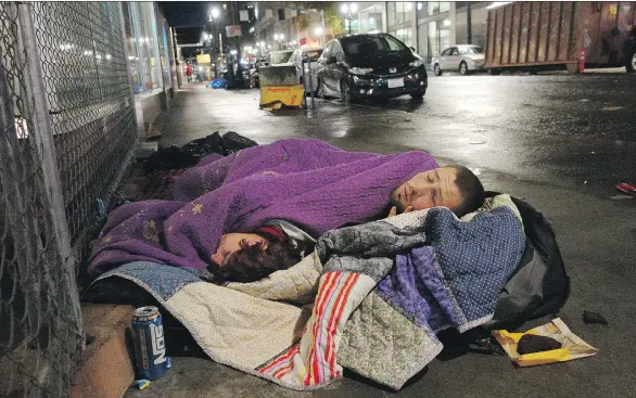  ?? TED S. WARREN/THE ASSOCIATED PRESS ?? Taz Harrington, right, sleeps with his girlfriend, Melissa Ann Whitehead, on a street in downtown Portland, Ore.