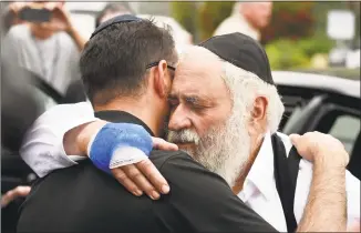  ?? Denis Poroy / Associated Press ?? Rabbi Yisroel Goldstein, right, is hugged as he leaves a news conference at the Chabad of Poway synagogue on Sunday in Poway, Calif.