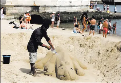  ?? Armando Franca ?? The Associated Press A man sprays water on his sand sculpture by the Tagus riverbank in Lisbon. Temperatur­es built to around 113 degrees Fahrenheit on Friday in many inland areas of Portugal and were expected to peak at 116.6 F in some places Saturday.