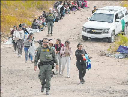  ?? Gregory Bull The Associated Press file ?? A Border Patrol agent leads a line of women to a van as they wait to apply for asylum in San Diego.