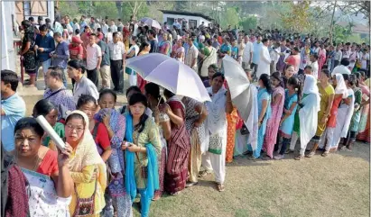  ??  ?? People wait in queues to cast their votes for the Lok Sabha polls at a polling station at Diphu in Karbi Anglong district of Assam on Saturday. — PTI