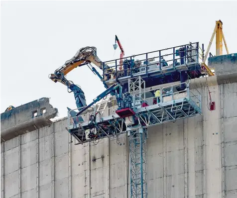  ?? Fotos: Thomas Frey, dpa (2)/Christian Kirstges (2) ?? Mühsame Kleinarbei­t: In Mülheim Kärlich tragen Arbeiter mit einer speziell entwickelt­en Maschine den Kühlturm ab. Bis das gesamte AKW abgerissen ist, wird es noch bis Mitte des nächsten Jahrzehnts dauern.