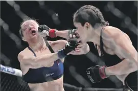  ?? Christian Petersen Getty Images ?? AMANDA NUNES delivers a crushing blow to the face of Ronda Rousey during Friday’s bout. Rousey never recovered from a barrage of first-round punches.