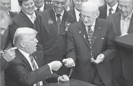  ?? POOL PHOTO BY OLIVIER DOULIERY ?? President Donald Trump gives a pen to astronaut Buzz Aldrin after signing an order to re-establish the National Space Council on June 30, 2017. On Monday, Trump called for “American dominance in space.”