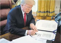  ?? AFP/ GETTY IMAGES ?? President Trump applies his signature to several bills Friday in the Oval Office.