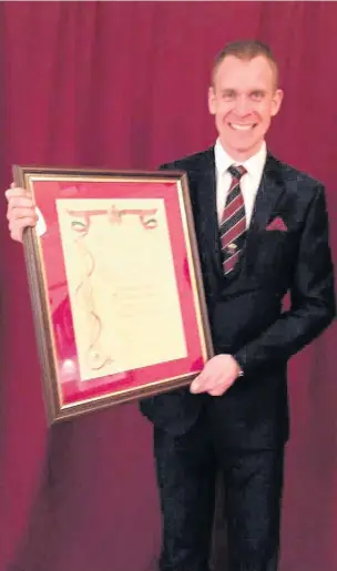  ??  ?? Cory’s musical director Phillip Harper with the framed Freedom of The Borough of Rhondda Cynon Taff presented to Cory Band in January