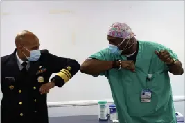  ?? YOUNGRAE KIM — CHICAGO TRIBUNE ?? Surgeon General of the U.S. Jerome Adams, left, elbow-bumps Emergency Room technician Demetrius Mcalister after Mcalister got the Pfizer COVID-19 vaccinatio­n at Saint Anthony Hospital in Chicago on Tuesday.