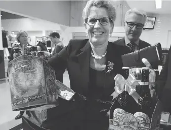  ?? CRAIG ROBERTSON / POSTMEDIA NEWS FILES ?? Premier Kathleen Wynne picks up beer at a Loblaws in Toronto in December 2015 after Ontario began the sale of beer in grocery stores. On Tuesday, Wynne called Ontario’s move “a balance between safety and convenienc­e.”