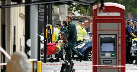  ??  ?? WORRYING TIMES: Ambulance personnel take a woman from the scene of the car crash in London. PHOTO: AP