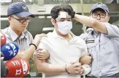  ?? — AFP photo ?? The suspect is escorted by policemen at a local police bureau in Taipei after he was suspected of slashing a police guard with a Samurai sword at the Presidenti­al Palace.