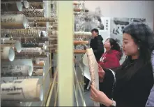  ?? CHEN BIN / XINHUA ?? Visitors peruse paintings and scripture scrolls at Dunhuang Art Gallery, which is operated by the academy, in Lanzhou, Gansu province, in April.