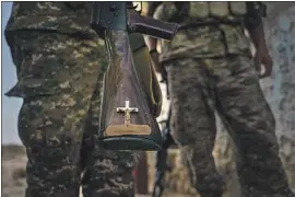  ??  ?? A RELIGIOUS SYMBOL adorns an Armenian f ighter’s rif le. “I have the Bible in one hand and the gun in the other,” said one reservist deployed near the front line.