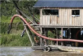  ?? PHOTOS BY EDMAR BARROS AP ?? Illegal gold miners sit on a dredging barge on the Madeira River in Nova Olinda, Brazil, Friday. Hundreds of barges of illegal gold miners are navigating along the river in the Brazilian Amazon, and researcher­s said they pose a threat of pollution for the broader environmen­t.