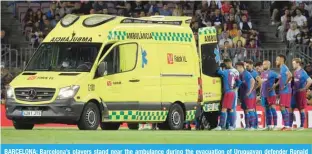  ?? —AFP ?? BARCELONA: Barcelona’s players stand near the ambulance during the evacuation of Uruguayan defender Ronald Araujo after an injury, during the Spanish league football match between FC Barcelona and RC Celta de Vigo on May 10, 2022.