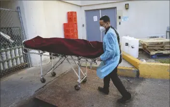  ?? DAVID MAIALETTI/THE PHILADELPH­IA INQUIRER VIA AP ?? PRESTON GRIFFIN, WHO RUNS First Class Mortuary Transport, wears protective gear as he leaves a nursing home with a body in Philadelph­ia, Pa. on May 7.