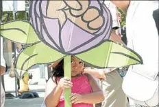  ?? Rebecca Lessner/Post-Gazette ?? Yarized Morales, 4, of Penn Hills holds a sign depicting a purple rose Sunday on the Roberto Clemente Bridge. “The rose and fist symbolize power, so that we know we have power,” said Navy veteran Patti Gerhauser of Cranberry (not pictured).