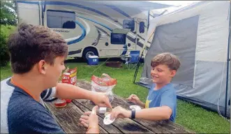  ?? FRANCK/ST. LOUIS POST-DISPATCH/TNS MATTHEW ?? Maxwell Franck, left, and Jackson Franck play a game of cards near their air-conditione­d tent at Lanier’s Campground in Holly Ridge, N.C. The RV in the background has a flatscreen TV on its exterior.