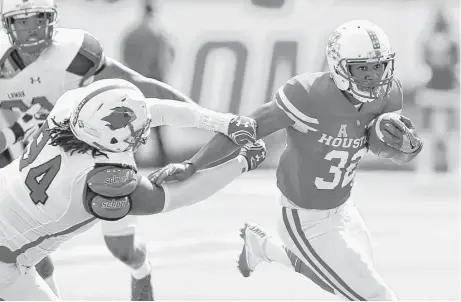  ?? Brett Coomer photos / Houston Chronicle ?? UH running back Kevrin Justice (32) gets away from Lamar defensive lineman Larry Carroll (94) as he breaks it to the outside.