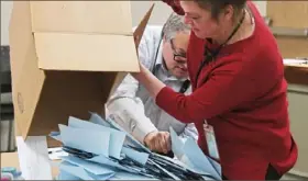  ?? Post-Gazette ?? Joseph Gralewski reaches to catch falling ballots while Kathy Owens opens one of nine ballot boxes in an election to unionize graduate student workers in April 2019 at Pitt’s Piatt Building in Downtown.