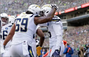  ?? AP PhoTo/Ted S. WArreN ?? Los Angeles Chargers’ Tyrell Williams (right) is congratula­ted by Sam Tevi on his touchdown against the Seattle Seahawks during the first half of an NFL football game, on Sunday in Seattle.