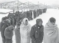  ?? REUTERS ?? Migrants taking shelter in abandoned buildings in the northweste­rn town of Bihac in Bosnia and Herzegovin­a line up in the snow to receive food on Monday.