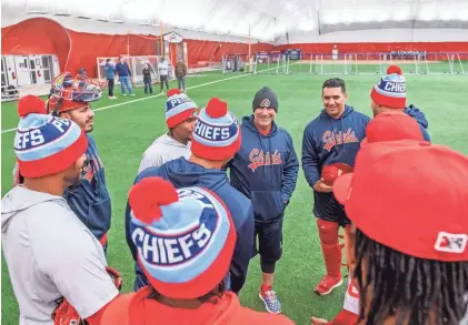  ?? PHOTOS BY MATT DAYHOFF/JOURNAL STAR ?? Peoria Chiefs manager Patrick Anderson, middle in stocking cap, talks with a group of his pitchers during practice Wednesday at the Louisville Slugger dome in Peoria.