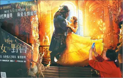  ?? LIU JUNFENG / FOR CHINA DAILY ?? A woman takes a photo of a poster for Beauty and the Beast at a cinema in Yichang, Hubei province.