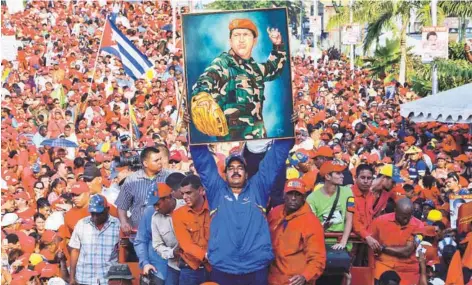  ??  ?? ► Maduro exhibe una pintura de Chávez durante un acto de campaña, en abril de 2013.