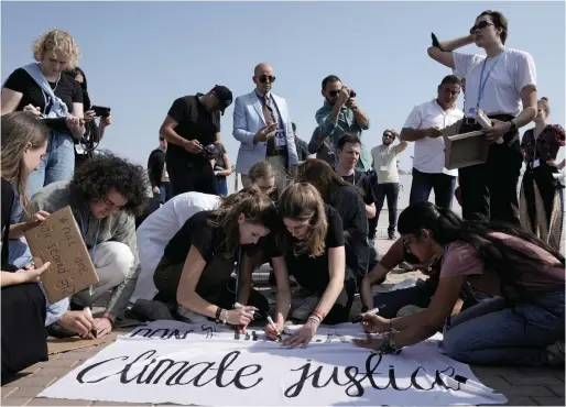 ?? ?? Climate activists work on a sign that reads “don’t be scared of climate justice” at the designated protest zone for the COP27 UN Climate Summit in Sharm El Sheikh, Egypt, on Tuesday. — ap