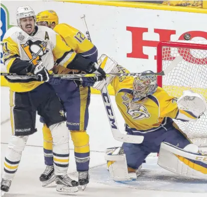  ??  ?? Predators goalie Pekka Rinne stops a shot as Mike Fisher battles the Penguins’ Evgeni Malkin during the third period of Game 3. | AP