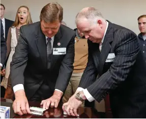  ?? (Photo by Rogelio V. Solis, AP) ?? In this file photograph taken Nov. 20, 2015, then Rep. Bo Eaton, D-Taylorsvil­le, left, and Republican challenger Mark Tullos, right, open and display the contents of silver-plated business card boxes after “picking straws” in the governor’s office near...