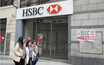  ?? — Reuters ?? Pedestrian­s walk past a closed HSBC branch in Buenos Aires, Argentina.