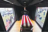  ?? DAVID J. PHILLIP/THE NEW YORK TIMES ?? Mourners line both sides of the track Thursday as the train carrying the coffin of former President George H.W. Bush passes by en route to his final resting place.