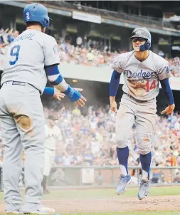  ?? Ap / jim gensheimer ?? El boricua Kike Hernández, de frente, se acerca a su compañero Yasmani Grandal para celebrar un par de carreras anotadas de los Dodgers.