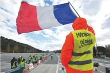  ?? AFP ?? A man with a sign reading ‘Macron resign’ waves a French flag amid the protest at La Barque, near Marseille.